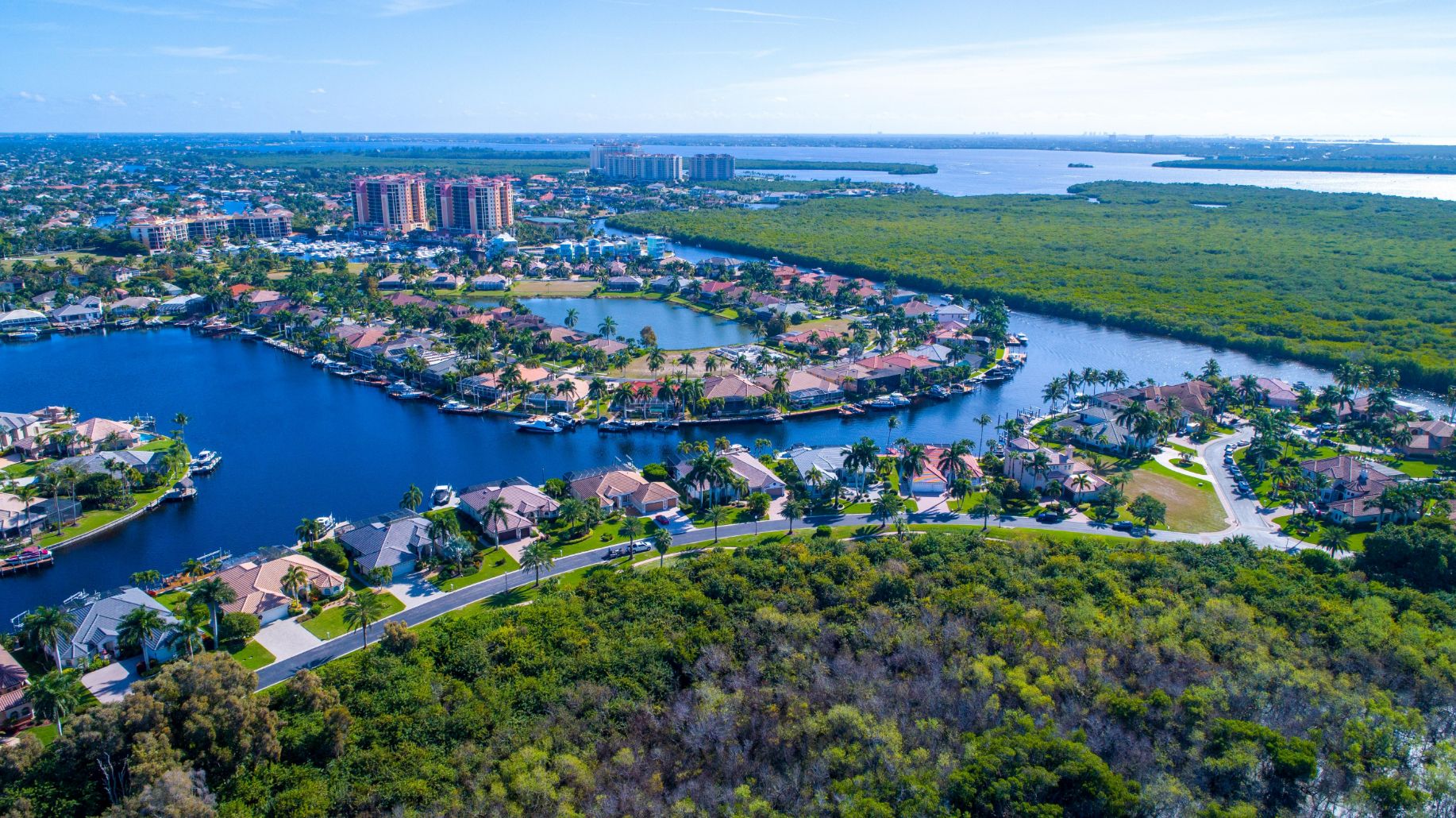 Aerial Drone View of Bay in Cape Coral, Florida with Mangroves and Real Estate in the Foreground and the Caloosahatchee River in the Background