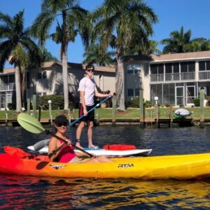 A kayak and paddle board on a calm, palm-lined freshwater canal